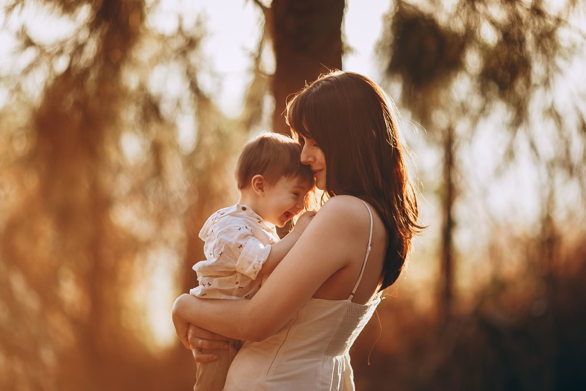 A parent holding their toddler close in warm evening light